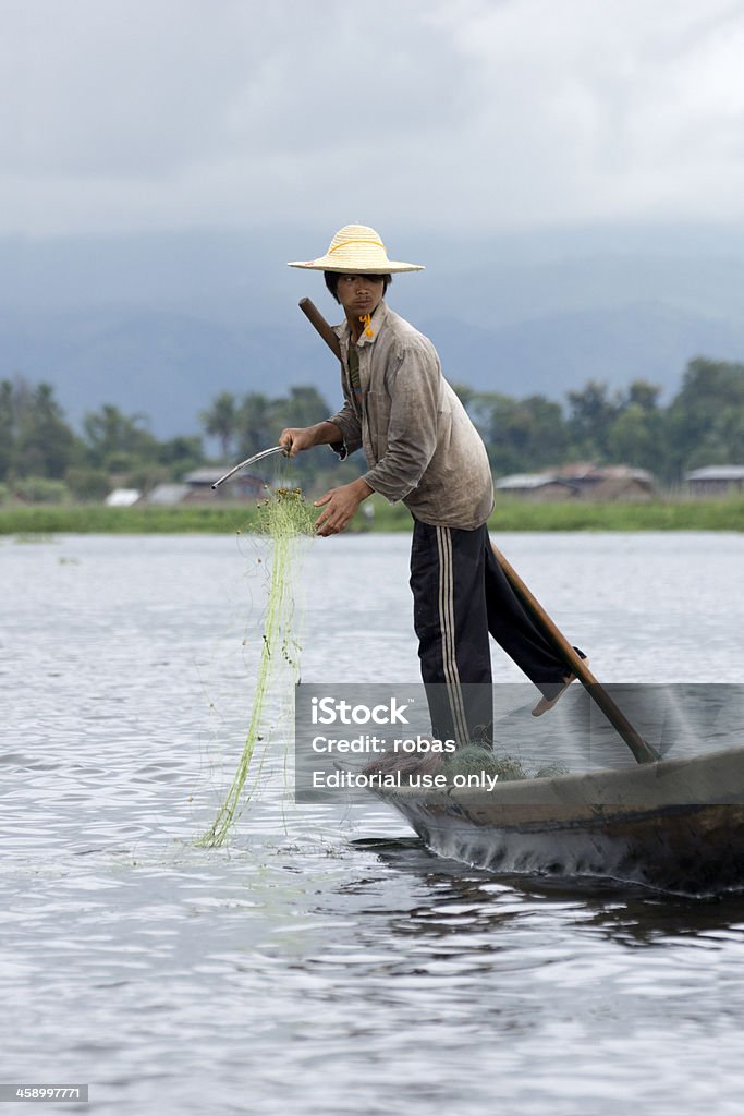 Birmano muelle de pie en una canoa, lago Inle - Foto de stock de Adulto libre de derechos