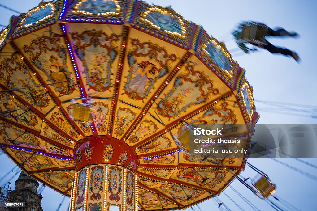 Chair-O-Plane Ride "Glasgow, UK - December 30, 2012: A young man rides the illuminated Chair-O-Plane chain swing ride in the early evening in Glasgow's  George Square during the Glasgow Loves Christmas winter festival." Chain Swing Ride Stock Photo