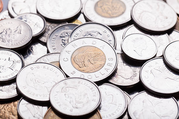 Canadian Currency "Calgary, Canada - February 26, 2013: A studio shot of a pile of current, modern day, legal tender Canadian coins." loonies and toonie stock pictures, royalty-free photos & images