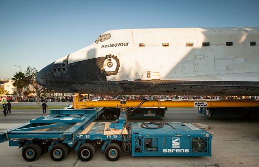 Los Angeles, California, USA - October 13, 2012: Large crowds of people line Crenshaw Blvd in Los Angeles to watch the Space Shuttle Endeavor as it travels through the streets on it's way to it's new home at the Science Center. Several police and a worker can be seen walking in front of the shuttle to make sure the way is clear.