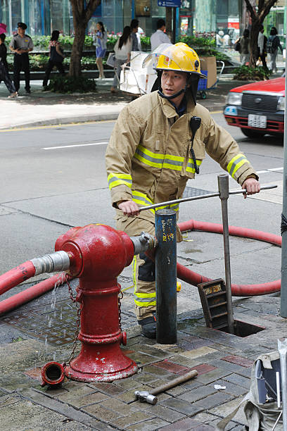 A yellow fire hydrant open and gushing water on a sidewalk downtown.