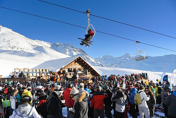 After Skiing Val Thorens, France - January 22, 2013: People having a drink at the popular La Folie Douce bar at the ski piste near Val Thorens on a beautiful sunny day. Skiers are sitting in the overhead chair lift. apres ski stock pictures, royalty-free photos & images
