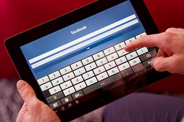 facebook página exibida em um tablet. - iphone google holding telephone - fotografias e filmes do acervo
