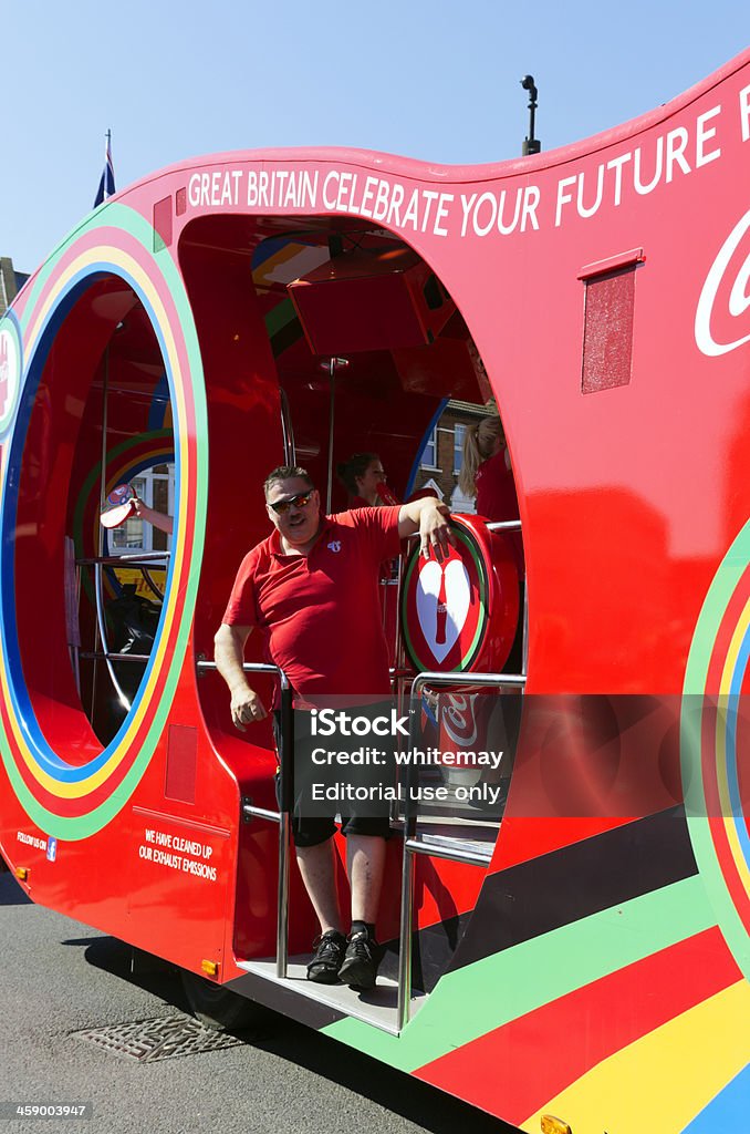 Olympic Torch Relay - Coca Cola vehicle "Beckenham, England - July 23, 2012: A man riding on a float in the Olympic Torch Relay procession as it make sits way through the streets of Beckenham (South East London), in Kent on 23rd July 2012. The torch was preceded by sponsors vehicles and much flag-waving - this particular sponsor was Coca-Cola. (Very strong sunshine.)" 2012 Stock Photo