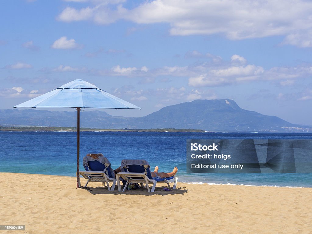 Sosua Beach, Dominican republic "Sosua, Dominican Republic - February 25, 2013: People can be seen on the beach in the morning sitting under a beach umbrella at Sosua on the northern coast of the Dominican republic." Beach Stock Photo