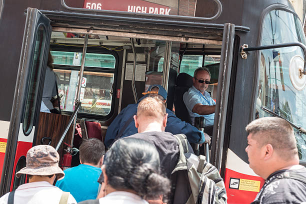 Boarding a Street Car "Toronto, Canada - May 22, 2012: A Toronto Transit Commission driver opens the street car doors for a crowd of commuters to board with High Park as the destination." sustainable energy toronto stock pictures, royalty-free photos & images