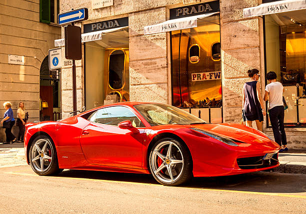 Red Ferrari in Milan, Italy "Milan, Italy - October 01, 2011: A bright Red Ferrari F430 sports car is parked at the corner of Via Spiga in the fashion district heart of Milans high-class shopping district, people in the background." park designer label stock pictures, royalty-free photos & images