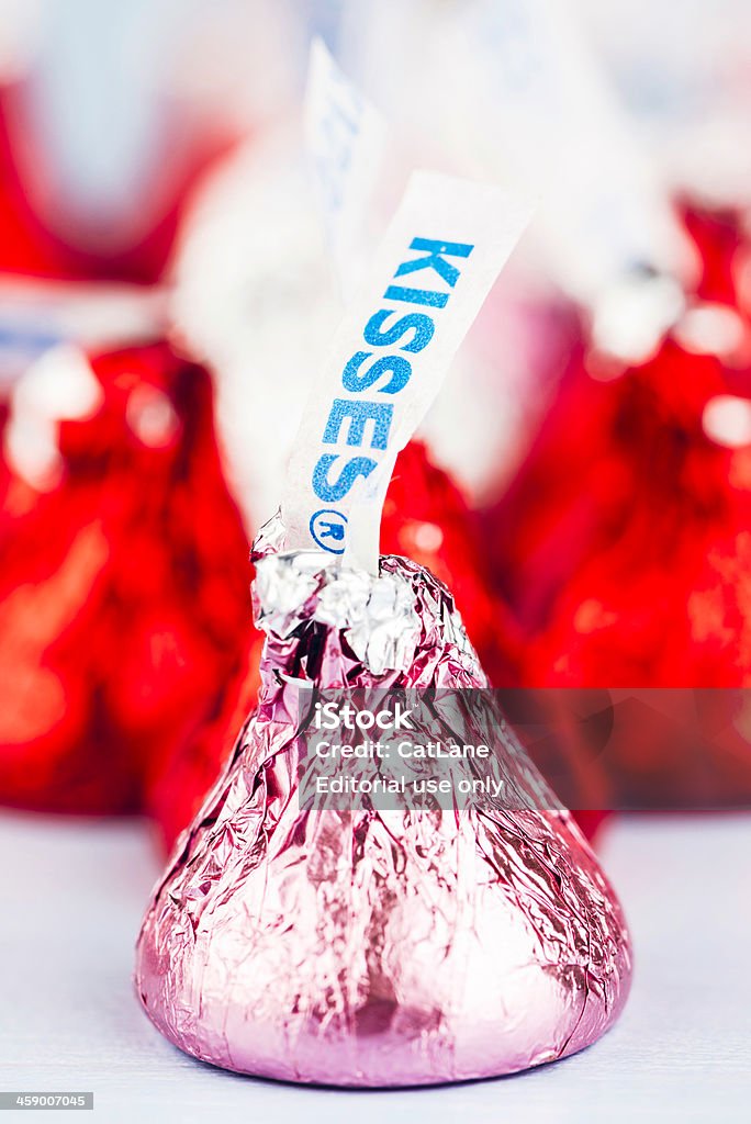 Hershey's Kisses Candy for Valentine's Day "Suffolk, Virginia, USA - January 11, 2013: A vertical studio shot of a Hershey Kisses chocolate candy wrapped in pink foil for Valentine's Day. Defocused in the background are more of the chocolate candies, wrapped in bright red and silver foil." American Culture Stock Photo