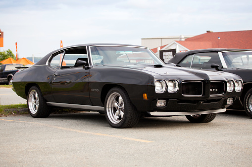 Dartmouth, Nova Scotia, Canada - June 14, 2012: At a public car gathering, a classic Pontiac GTO parked in a parking lot with its windows down.  Other vintage automobiles are visible to the left of vehicle and behind.