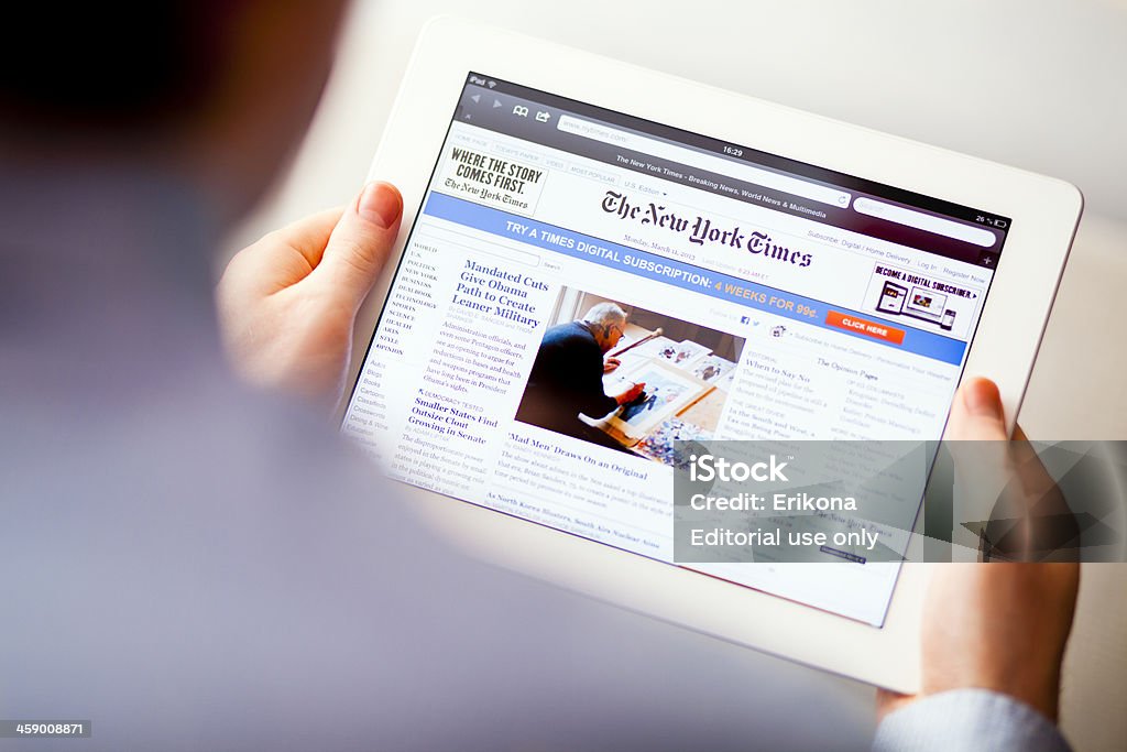 The New York Times Nizhnevartovsk, Russia - March 11, 2013: Man reading The New York Times to iPad. The New York Times is an American daily newspaper, founded and continuously published in New York City since 1851. iPad product by Apple Inc. New York Times Stock Photo