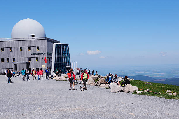 Peak of Brocken Mountain at Harz National Park (Germany) "Brocken, Germany - May 26, 2012: Peak of Brocken Mountain at Harz National Park (Saxony-anhalt, Germany) with its Brockenhaus (Information house of Harz National Park). In front a group of people walking with a dog and others resting on rocks enjoying the landscape." sendemast stock pictures, royalty-free photos & images