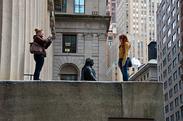 Tourists at Federal Hall, Wall Street, Lower Manhattan, NYC "New York City, USA - March 29, 2013: Two young women tourists seen at historic Federal Hall, 26 Wall Street in Manhattan's Financial District, the site of the inauguration of George Washington as the first President of the United States." nassau street stock pictures, royalty-free photos & images