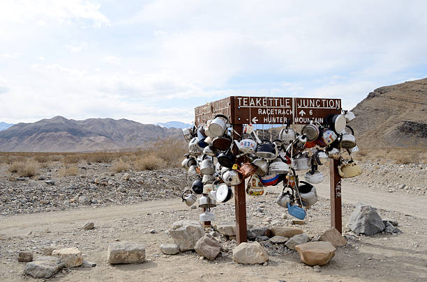 teakettle junction in death valley Death Valley National Park, USA - February 19, 2012: The Teakettle Junction sign, visitors travel to the area and leave teakettles and teapots, which often have messages written on them. teakettle junction stock pictures, royalty-free photos & images