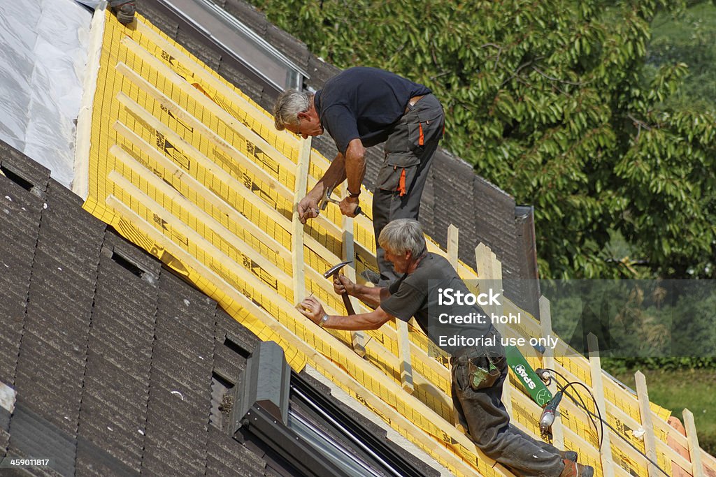 roofer at work "Zirndorf, Germany - May 25, 2010: Two roofers with hammer and nails working on a roof on a sunny day." Adult Stock Photo