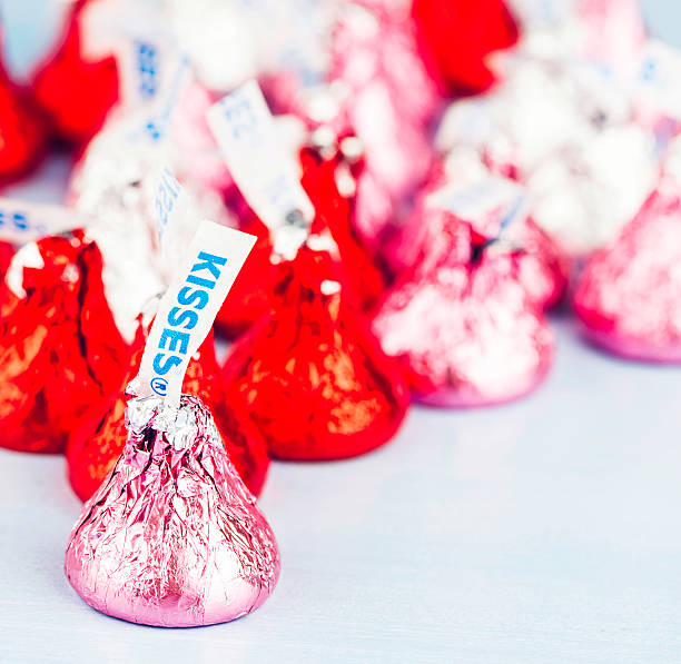 Hershey Kisses Candy for Valentine's Day "Suffolk, Virginia, USA - January 11, 2013: A square format studio shot of Hershey Kisses chocolate candies wrapped in pink, red and silver foil for Valentine's Day." hersheys kisses stock pictures, royalty-free photos & images