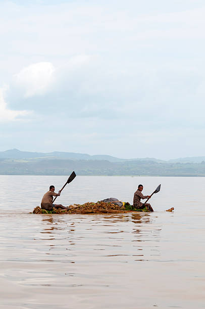 Lake Tana, Ethiopia - August 19, 2010: Two Ethiopian men row their loaded homemade raft on Lake Tana during a misty afternoon. The lake is best known for its many island monasteries, and as the source for the Blue Nile.