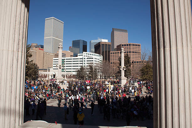 Martin Luther King Jr. Day march arrives in Denver "Denver, Colorado, U.S.A. - January 21, 2013: Looking in between large columns at the end of a Martin Luther King Jr. Day parade, a diverse crowd of people gather at Civic Center Park with the downtown skyline in the background." martin luther king jr day stock pictures, royalty-free photos & images