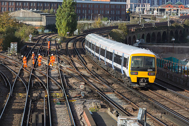 Rail track maintenance "London, UK - November 5, 2012: A team of rail track maintenance workers inspecting and repairing a railway track while a train passes by during the day in London." wandsworth photos stock pictures, royalty-free photos & images