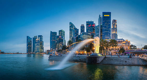 Singapore Merlion Fountain CBD skyscrapers overlooking Marina Bay at dusk "Singapore, Singapore - 14th February 2012: The crowded cityscape of Central Business District skyscrapers overlooking the Merlion fountain on the Marina Bay waterfront at dusk as tourists and locals enjoy the warm evening promenade, Singapore. Composite panoramic image created from six contemporaneous sequential photographs." singapore stock pictures, royalty-free photos & images