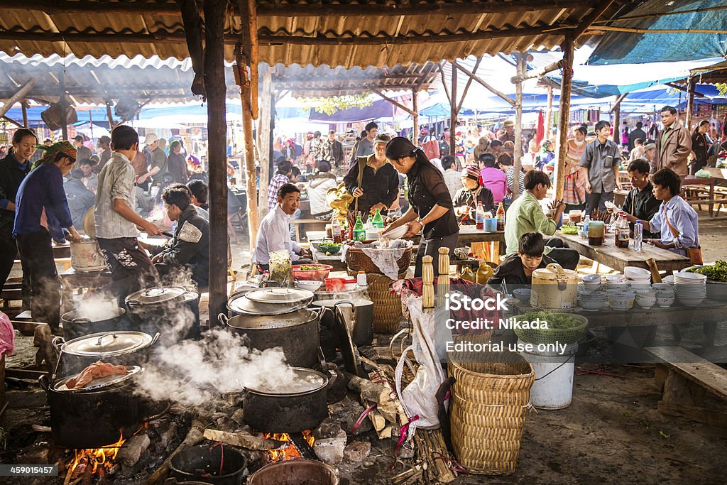 People eating at a street market in Vietnam "Bac Ha, Vietnam - November 18, 2012: People sitting and eating lunch at a street market. Bac Ha hosts the biggest fair near the mountainous highlands and the Chinese border." Vietnam Stock Photo
