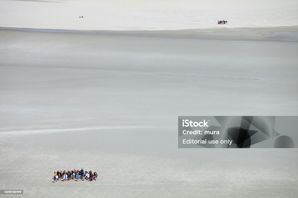 Os turistas trekking na lama praia na maré baixa - Foto de stock de Areia royalty-free