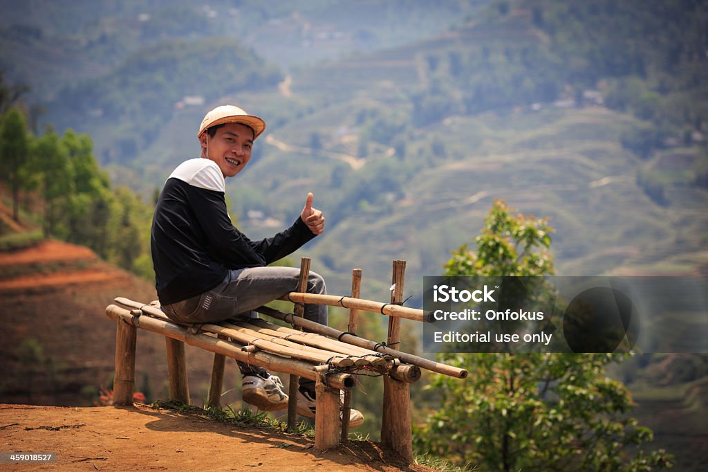 Vietnamese Man Thumb Up and Happy, Sa Pa, Vietnam Sa Pa, Vietnam - April 2, 2013: Vietnamese guide in Sa Pa, Vietnam.  Local guide sitting on a bench doing thumbs up. Adult Stock Photo