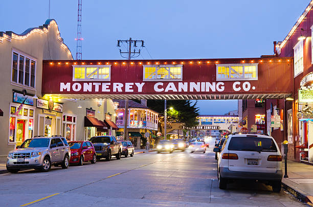 Cannery Row in Monterey, CA at night "Monterey, United States - July 1, 2012: Cars drive along the waterfront street of Cannery Row in the New Monterey section of Monterey. The area is the site of a number of now-defunct sardine canning factories, the last of which closed in 1973. Now, Cannery Row is a tourist attraction with many restaurants, shops and hotels." city of monterey california stock pictures, royalty-free photos & images