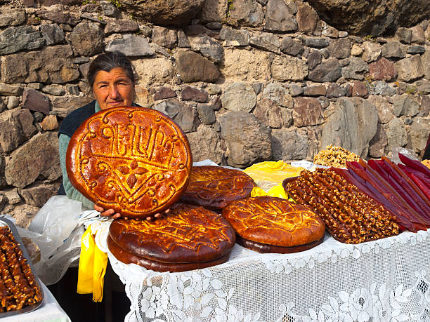Armenia Bread "Gerhard, Armenia - November 26, 2010: Woman is selling traditional Armenia bread on improvised stands on parking place in front of Gerhard monastery. In background is wall from the monastery and is on white traditional weaving lace tablecloth." armenia country stock pictures, royalty-free photos & images