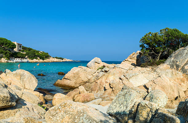 Sardinia "Cala di Volpe, Italy - September 10, 2012: Tourists taking a bath in the bay waters , in the background the Capriccioli promontory." Cala Di Volpe stock pictures, royalty-free photos & images