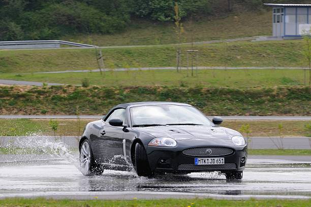 Gartzweiler, Germany - April 26, 2008: Jaguar XKR convertible driving through water during a skid training during a defensive driving course.