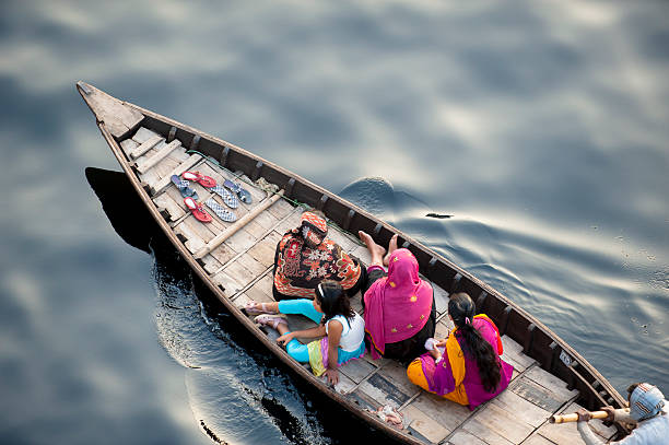 Boat carrying Bengalese on black water, Dhaka, Bangladesh "Dhaka, Bangladesh - February 18, 2013: A boat carrying Bengalese women dressing in traditional costume moving on black Buriganga River, Dhaka, Bangladesh." bangladesh photos stock pictures, royalty-free photos & images