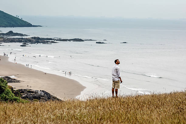August 13, 2021 - Llanes, Spain: Aerial view capturing tourists strolling, relaxing on golden sands of Barro beach, scenic coastal landscape in Llanes, Asturias, Spain under bright summer sunlight