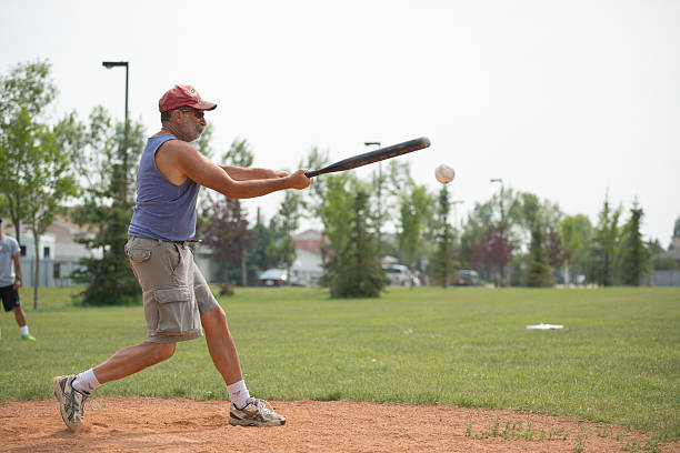 Senior male softball player "Edmonton, Canada - July 14, 2012: Man batting at softball gameSoftball is a variant of baseball played with and a larger ball on a smaller field.The name softball was given to the game in 1926.Despite the name, the ball used is not soft." old baseball stock pictures, royalty-free photos & images