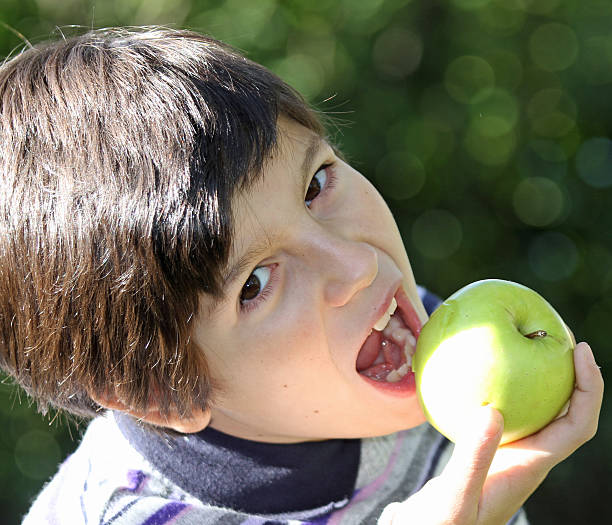 istock Kid eating a ripe apple green 459027377