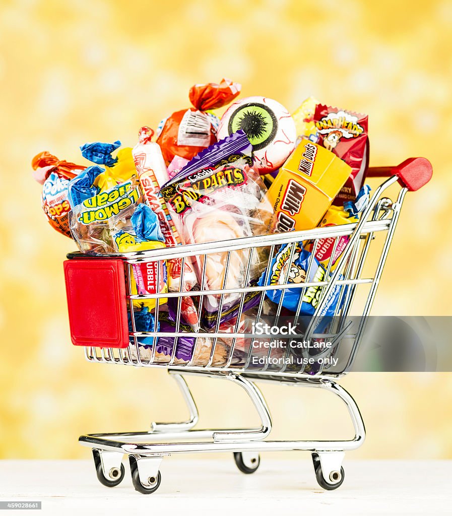 Shopping for Halloween Candy "Suffolk, Virginia, USA - October 9, 2012: A vertical studio shot of a miniature shopping cart filled with various candies from different American manufacturers that are sold for Halloween and Trick or Treating. Included in the cart are Milk Duds, Lemon Heads, Body Parts, WarHeads, Smarties, Nerds, Dubble Bubble and more." Shopping Cart Stock Photo