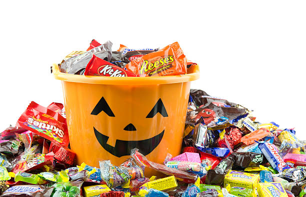 orange plastic halloween bucket filled and overflowing with candy - candy stok fotoğraflar ve resimler