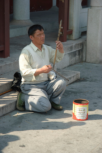 GUANGDONG,CHINA - February 6, 2011: Chinese blind beggar play two-stringed Chinese fiddle