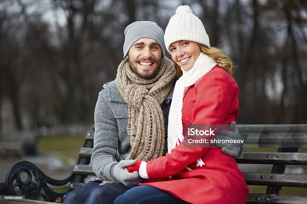 Happy dates Image of affectionate couple sitting on the bench and looking at camera in park Adult Stock Photo