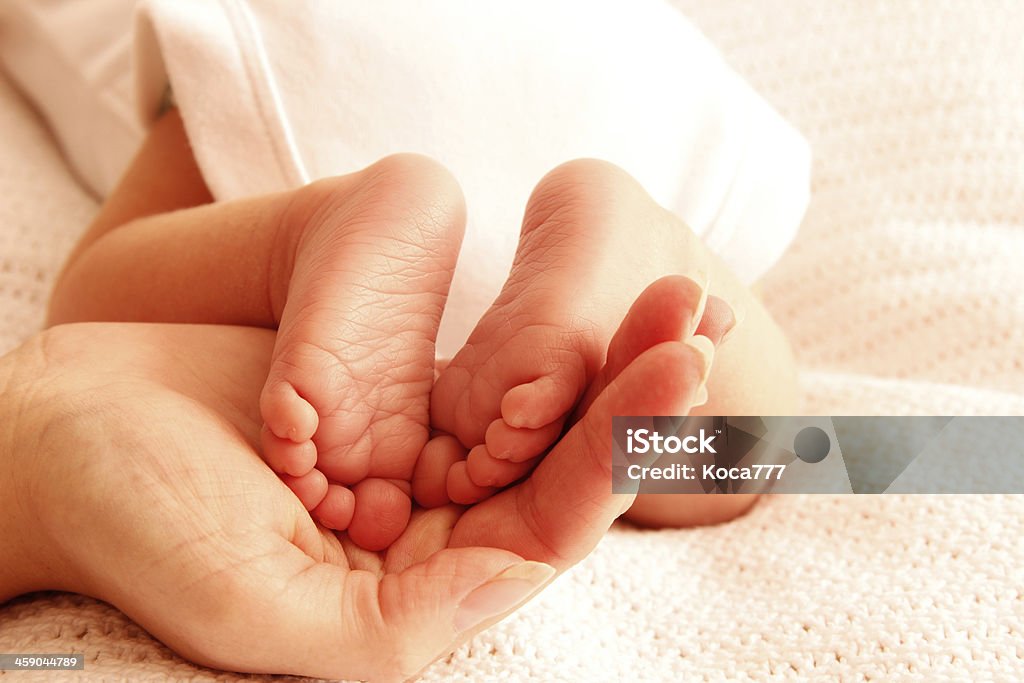 Mom holds the legs of cute newborn little baby a Mom holds the legs of cute newborn little baby Child Stock Photo