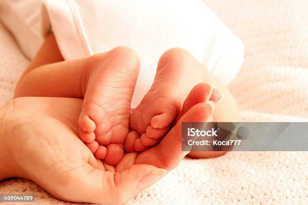 Mom Holds The Legs Of Cute Newborn Little Baby Stock Photo - Download Image Now - Child, Childhood, Cute