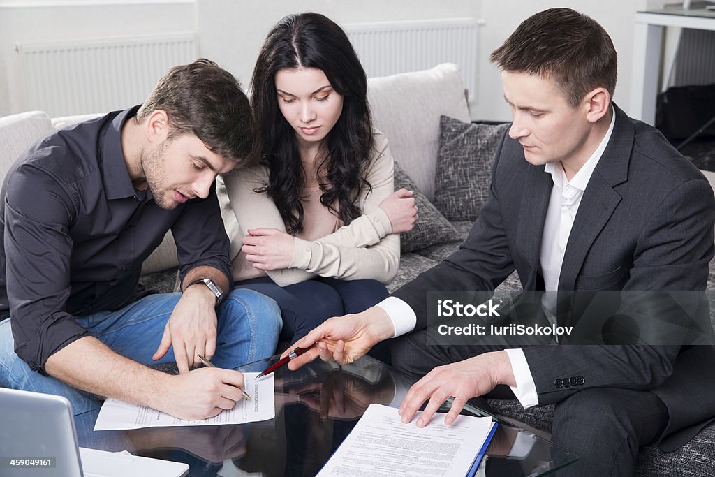 Couple signing documents with agent couple consults with agent, signing paperwork Adult Stock Photo