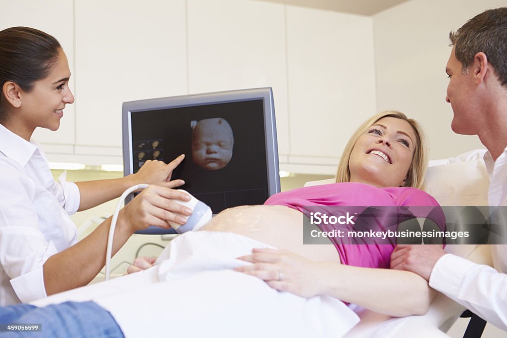 Pregnant Woman And Partner Having 4D Ultrasound Scan Layed Down Smiling Pregnant Woman And Partner Having 4D Ultrasound Scan Ultrasound Stock Photo