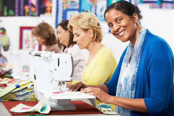 Group Of Women Using Electric Sewing Machines In class Group Of Women Smiling Using Electric Sewing Machines In class machine sewing white sewing item stock pictures, royalty-free photos & images