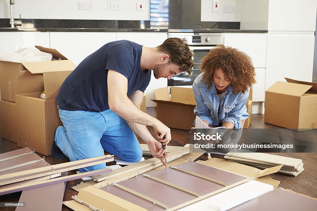 Couple Putting Together Self Assembly Furniture In New Home Young Couple Putting Together Self Assembly Furniture In New Home Furniture Stock Photo