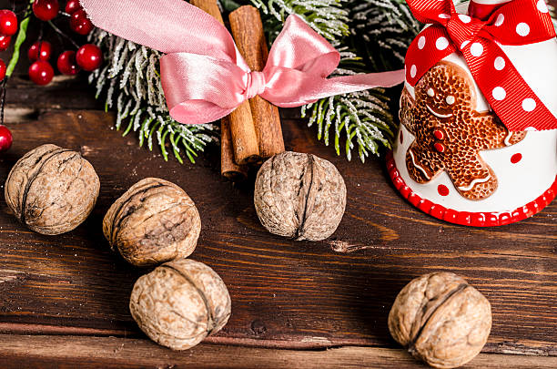 christmas bell, branches, cinnamon sticks and walnuts on wooden table stock photo