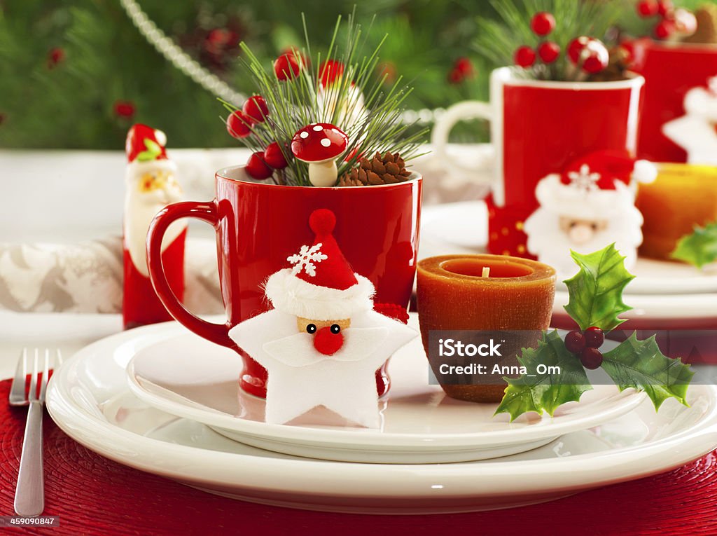 Christmas table setting Picture of beautiful Christmas table setting, shining white plate with red cup for coffee decorated holiday dinner, branch of berry and santa claus star on festive dishware, New Year party, xmas eve Banquet Stock Photo