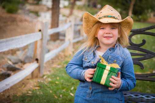 Adorable Young Girl Wearing Holiday Clothing Holding Christmas Gift Outside.