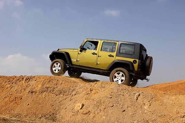 Rustenburg, South Africa -  May 18, 2013: Green Jeep Wrangler Unlimited scaling tilted sand hill obstacle at new 4x4 track opening event  at Bafokeng.