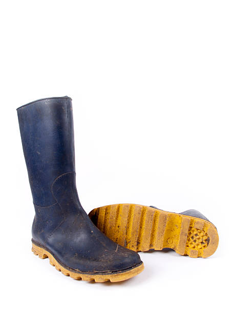 Pair of dark blue dirty rubber boots over a white background