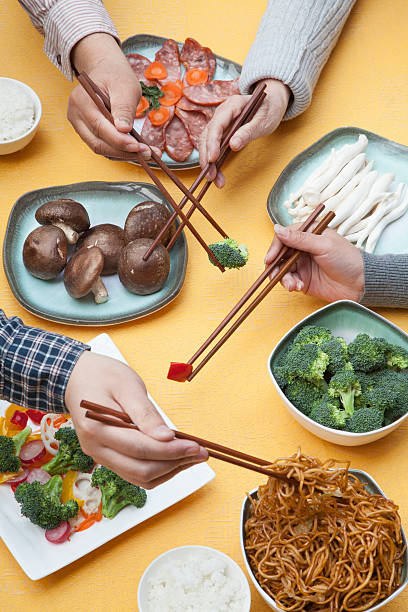 Close up of people using chopsticks with Chinese food